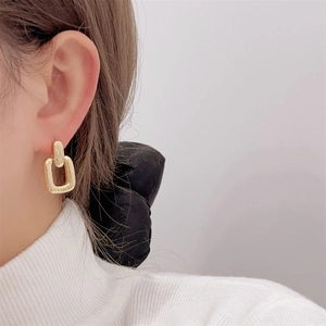 Close-up of elegant gold geometric rectangular drop earrings worn by a model