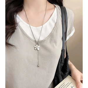 Elegant silver flower pendant necklace with central pearl on a long chain shown on model