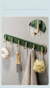 Detail view of J-shaped gold hooks on a green adhesive bar for bathroom storage