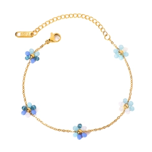 Gold stainless steel chain bracelet with blue and white beaded floral charms on white background