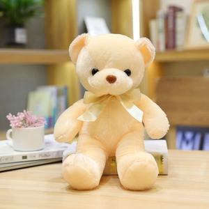 Lindo osito de peluche beige crema con un lazo de cinta a juego en postura sentada