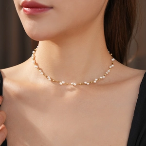 Detail of double-layer woven pearl necklace with gold chain on model's neck