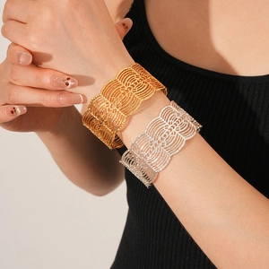 Detail der breiten Gitter-Manschettenarmbänder in Gold und Silber am Model