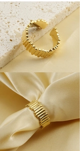 Detailed view of adjustable golden pleated ring with vertical striped texture on marble