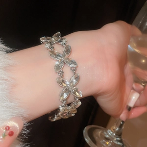 Sparkling crystal flower bracelet on wrist holding a glass in elegant night lighting