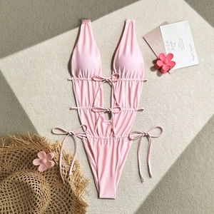 Flat lay detail of pink one-piece swimsuit featuring side cut-outs and lace-up ties