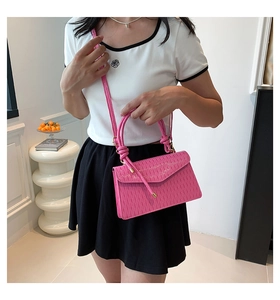 Detail of bright pink pleated handbag with a round handle and adjustable strap