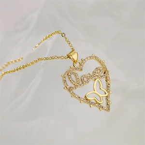 Macro detail of gold heart necklace featuring Love script, butterfly and sparkling crystals