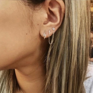 Detailed close-up of S925 silver lightning stud and star chain earrings on model