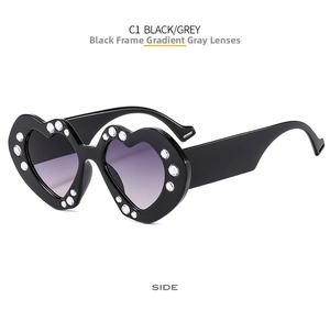 Detail view of heart-shaped black sunglasses with sparkling rhinestone trim and grey lenses