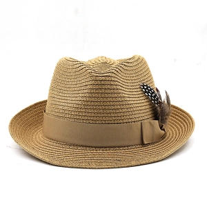 Detail of brown straw fedora hat featuring a wide ribbon and decorative feathers