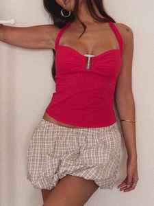 Dettaglio del top rosso a lupetto con gancio a T e gonna a sbuffo beige a quadri