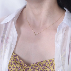 Close-up of elegant V-shaped gold necklace with pavé diamonds worn by a female model