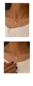 Detail view of gold crescent moon pendant featuring a deep blue center gemstone