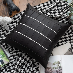 Close-up of black leather cushion cover with white stripes and metal hardware accents