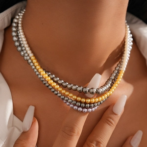 Elegant multi-layered pearl necklace with white, gold, and grey beads on female model