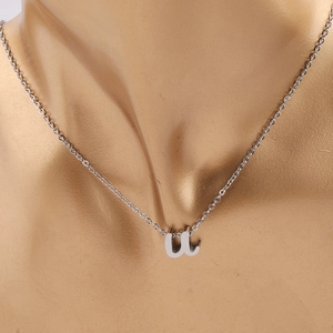 Détail d'un collier en acier inoxydable argenté avec un pendentif lettre u sur un mannequin