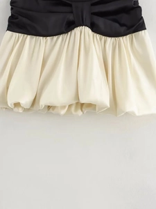 Detailansicht der kontrastierenden schwarzen Bundfalten und Creme-Satin-Ballonrock-Struktur