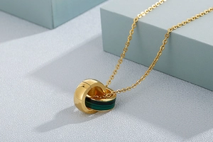 Close-up of interlocking gold rings necklace with a deep green stone inlay detail