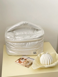 Detail of pearl white quilted makeup bag with soft downy texture and sturdy top handle