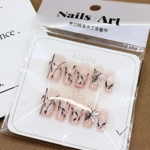 Pink glitter press-on nails with black butterfly patterns and silver rhinestones