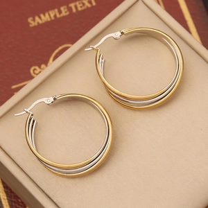 Macro shot of geometric two-tone stainless steel hoop earrings in a velvet jewelry box
