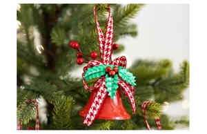 Close-up of a red Christmas bell with a houndstooth bow and holly leaves on a tree