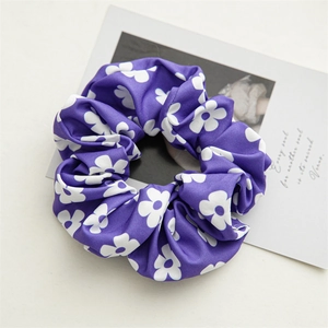 Detail of purple floral scrunchie with white flower patterns and soft fabric texture