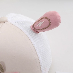 Close-up of breathable mesh and embroidered pink ears on a beige kids' baseball cap