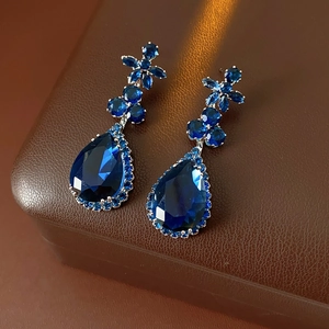 Detailed macro view of dark blue teardrop zircon earrings with flower-shaped stud accents