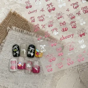 Macro detail of cherry and bow nail stickers with pink glitter on various nail tips