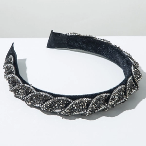 Dettaglio del cerchietto in velluto nero con design a treccia e cristalli argentati densi