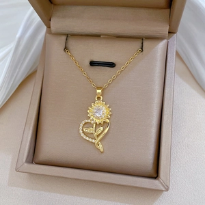 Close-up of golden sunflower and heart pendant set with white zircons in a jewelry box