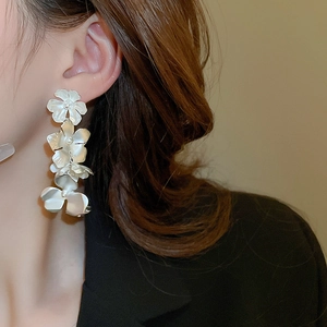 Close-up of elegant long cascading white matte flower earrings worn by a model