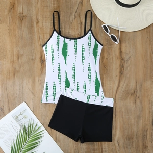 Flat lay of green abstract striped tankini top and black boy-short bottom on wood
