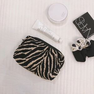 Minimalist zebra stripe boat-shaped makeup bag with textured fabric and zipper closure