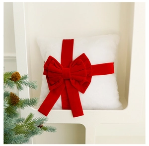 Close-up of white faux fur pillow with oversized red velvet bow for Christmas decor