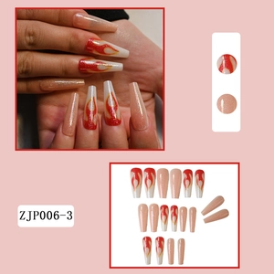 Detail view of long press-on nails featuring nude glitter and red flame designs