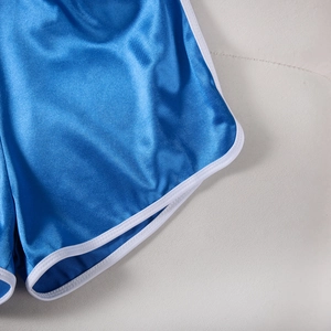 Detail shot of blue satin sports shorts with white contrast piping and smooth texture