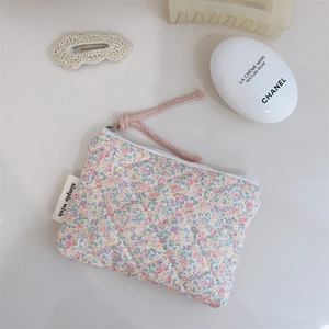 Détail de la pochette matelassée à fleurs avec étiquette 'simple wish' et fermeture