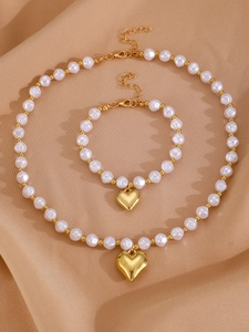 Détail du collier et bracelet avec pendentif coeur doré et perles sur tissu en soie