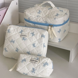 Quilted 3-piece makeup bag set in cream with blue bow patterns and zipper