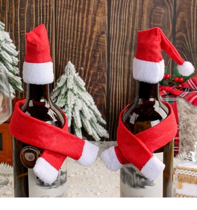 Detailed view of red non-woven Christmas hat and scarf set on a wine bottle
