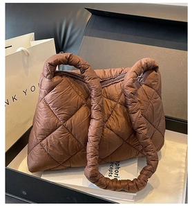 Detailed view of brown quilted nylon tote bag placed among elegant gift boxes