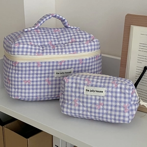 Detail of purple checkered quilted cosmetic bags with pink bow patterns in lifestyle setting