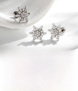 Macro shot of silver snowflake ear studs with zircon stones and polished steel base