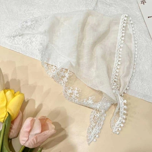 Detail of white lace triangle scarf featuring intricate floral crochet and elegant ribbons