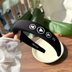 Detail view of black padded headband featuring white media icons and premium satin texture
