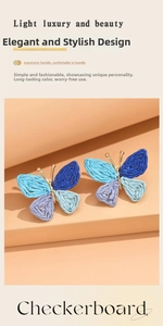 Detail shot of hand-woven raffia butterfly earrings with gold-toned metal accents