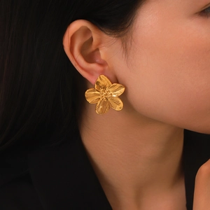 Detail of 18K gold textured flower earring on ear with polished stainless steel finish